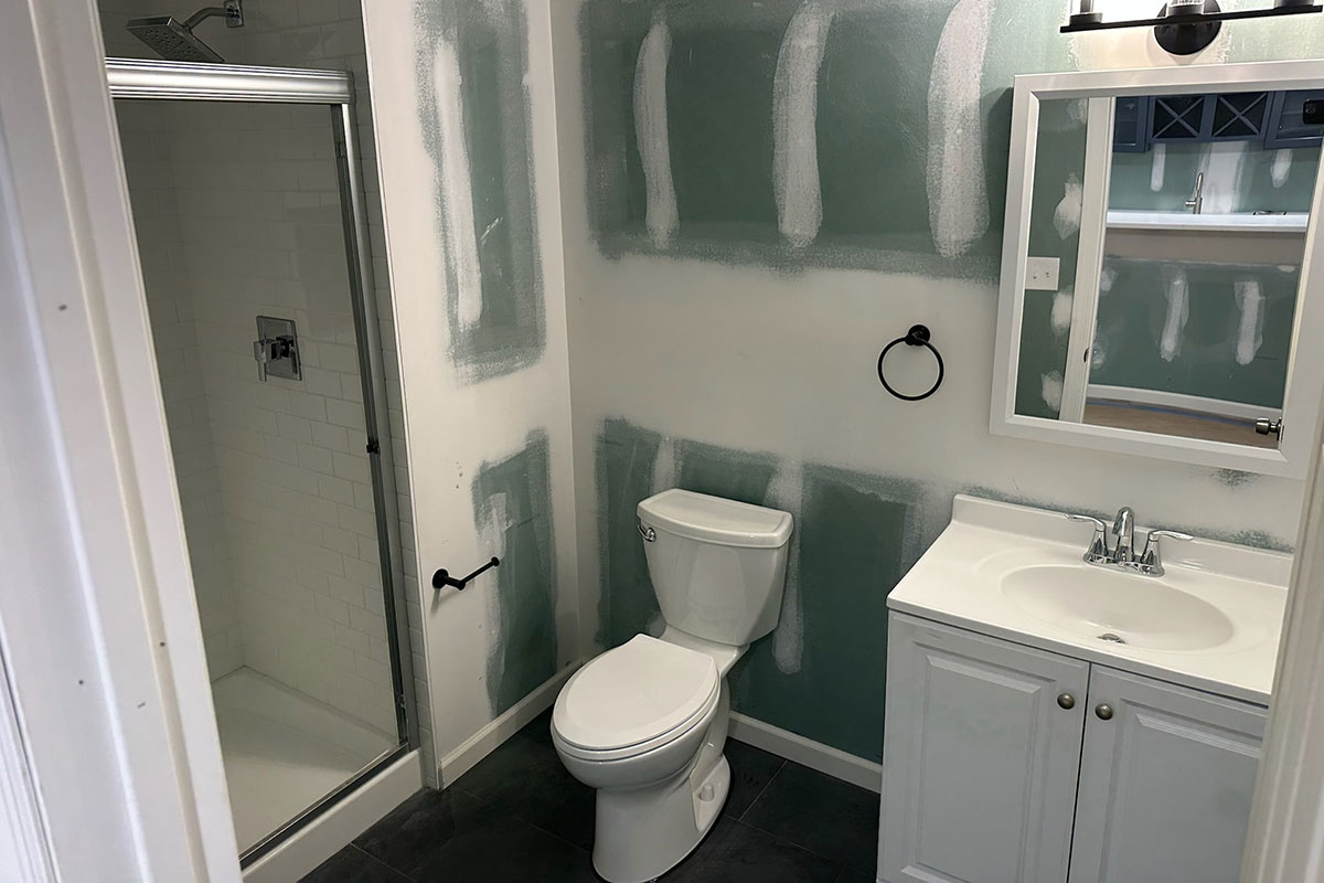 Totally Plumbing - Finished plumbing installation including vanity, sink, faucet, toilet, stall shower, and shower trim for a full bathroom and sink, faucet, and ejector tank for a bar in a finished basement in Princeton, New Jersey – November 2023